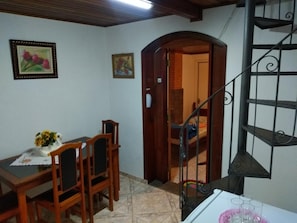 A dining area with a wooden table and chairs, a vase of flowers, and a staircase with a metal railing.