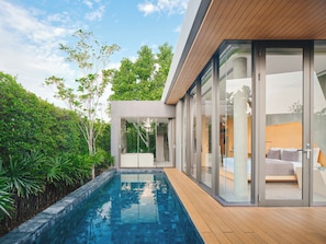 A modern house with a swimming pool, large glass doors, and a view of the garden.