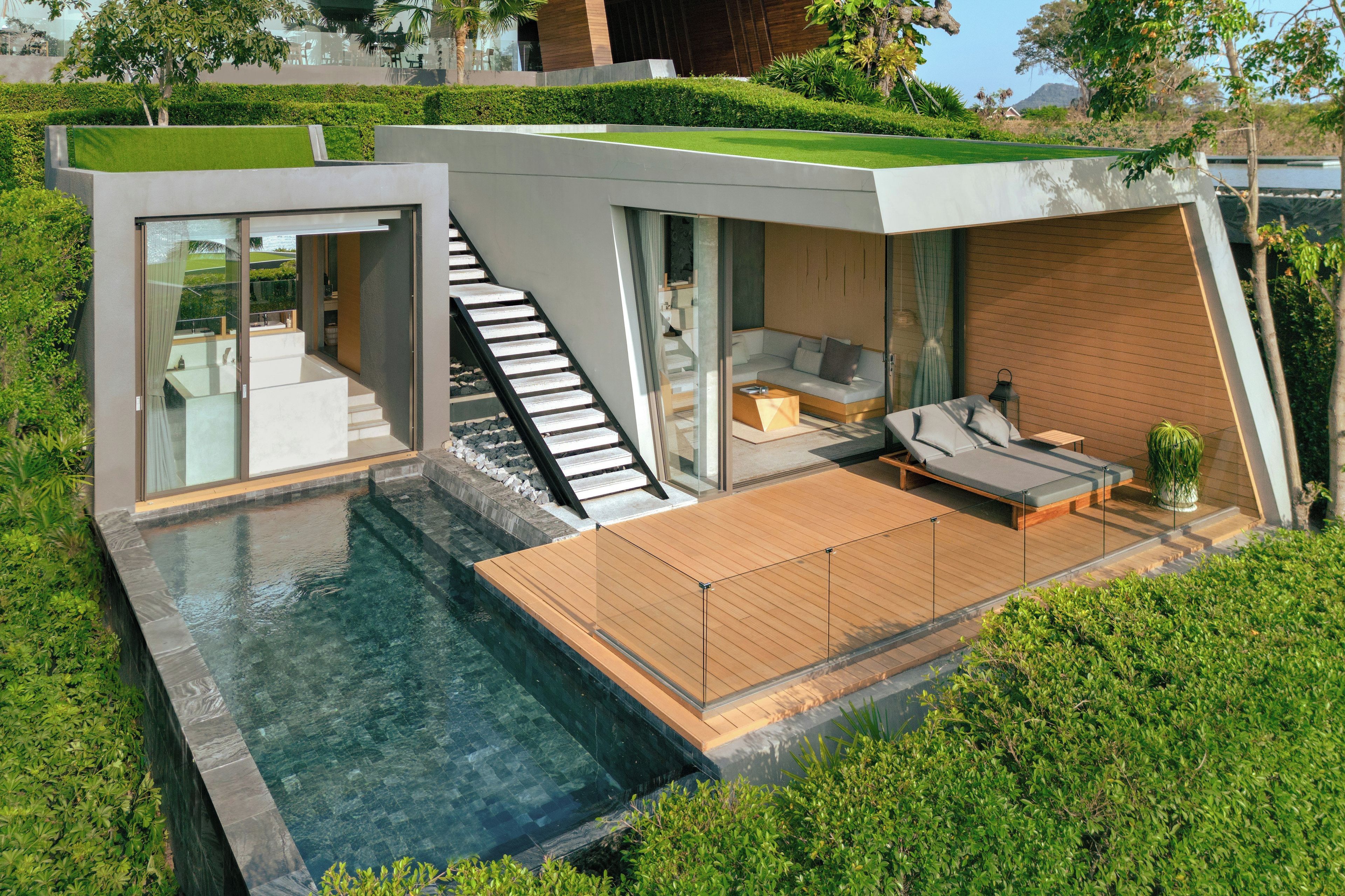 A modern house with a glass staircase, a pool, and a wooden deck.
