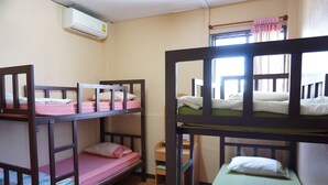 A dormitory room with bunk beds, a window with curtains, and an air conditioning unit on the wall. - OYO 730 Meedee Hostel (Bangkok)