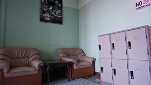 A room with two leather armchairs, a small table, and a set of lockers. - OYO 730 Meedee Hostel (Bangkok)
