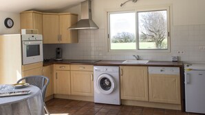 Una cocina compacta con lavadora, cafetera y un reloj en la pared.