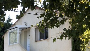 Un edificio con una escalera de concreto que lleva a una puerta, una ventana pequeña y una lámpara fijada a la pared.