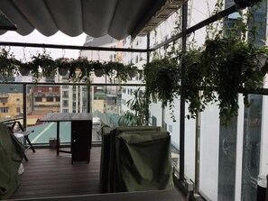 Un balcón con vistas a edificios, cubierto por un toldo y amueblado con una mesa y sillas.