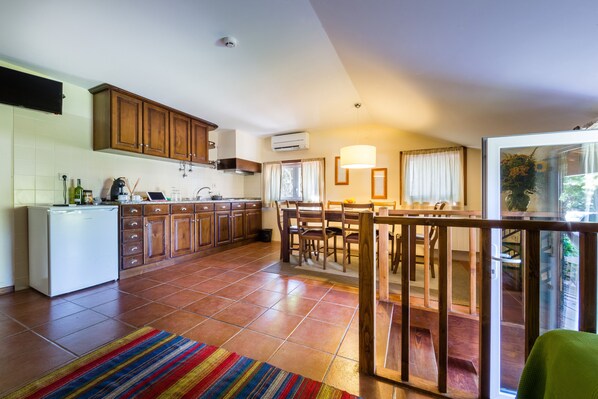 A spacious kitchen with wooden cabinets, a white refrigerator, and a dining area with a table and chairs. - Quinta da Pousadela (Amarante)