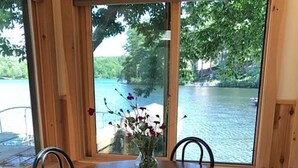 A wooden dining table with four black chairs and a vase with flowers. - Relax on Crescent Lake  #2 (Wolfeboro)