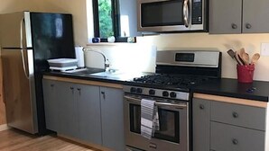 A modern kitchen with grey cabinets, stainless steel appliances, and a wooden ceiling. - Relax on Crescent Lake  #2 (Wolfeboro)