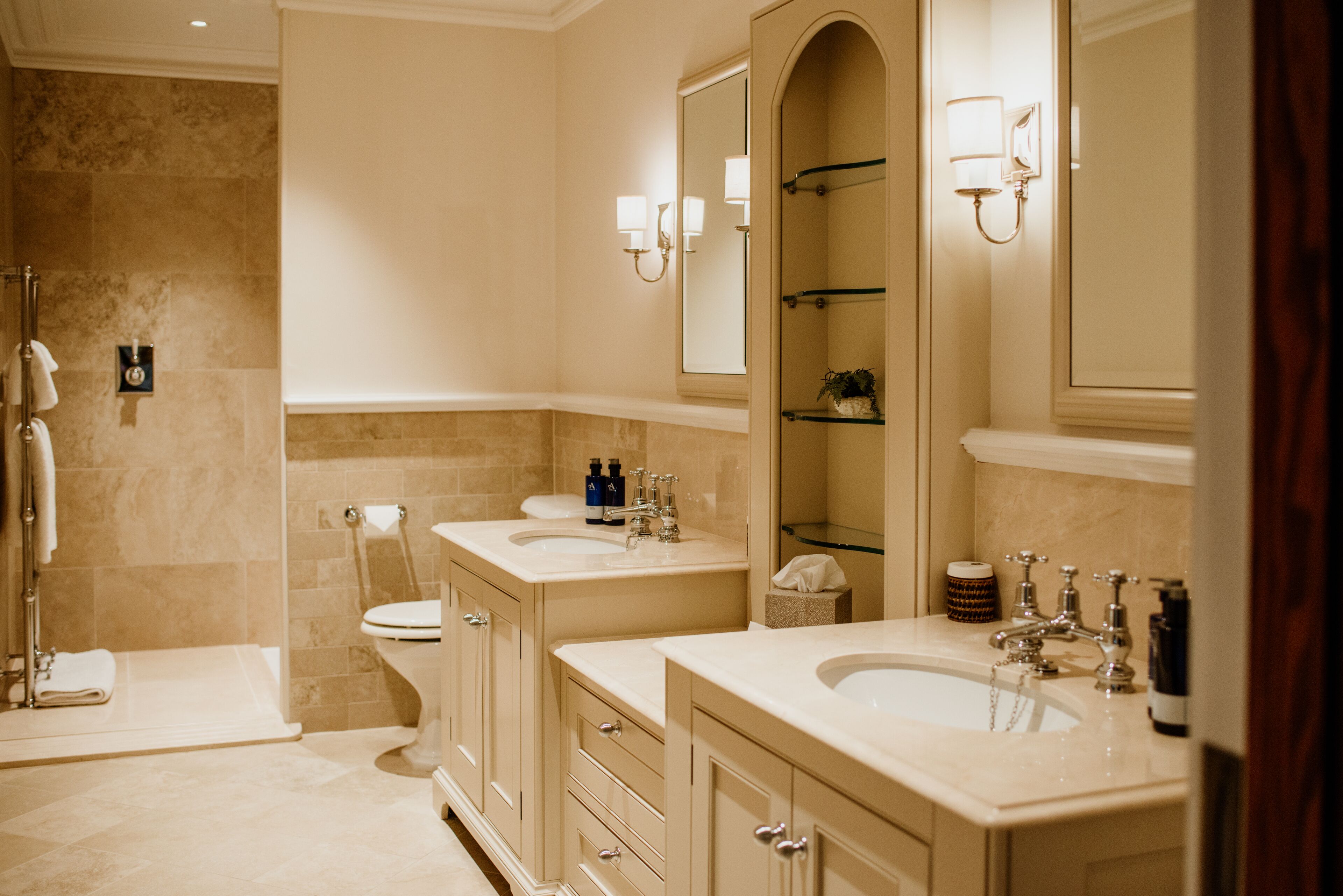 Un baño moderno con dos lavamanos, cabina de ducha de vidrio y un espejo grande.
