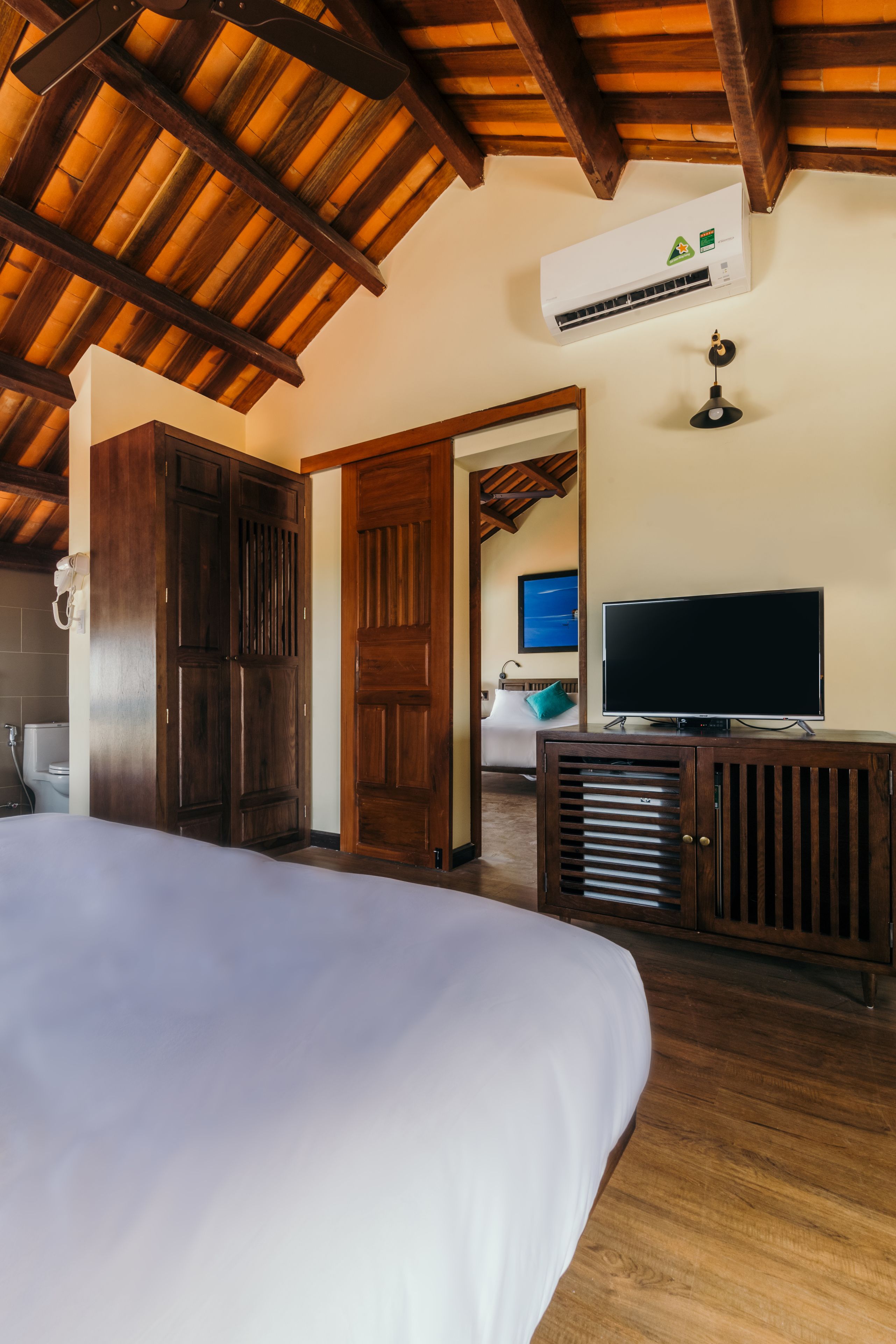 Un dormitorio con una cama grande, armario de madera, televisor y aire acondicionado.
