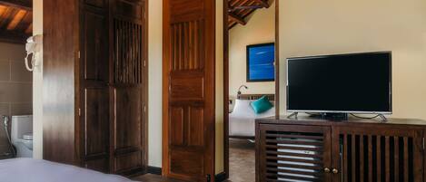 Un dormitorio con una cama grande, armario de madera, televisor y aire acondicionado.
