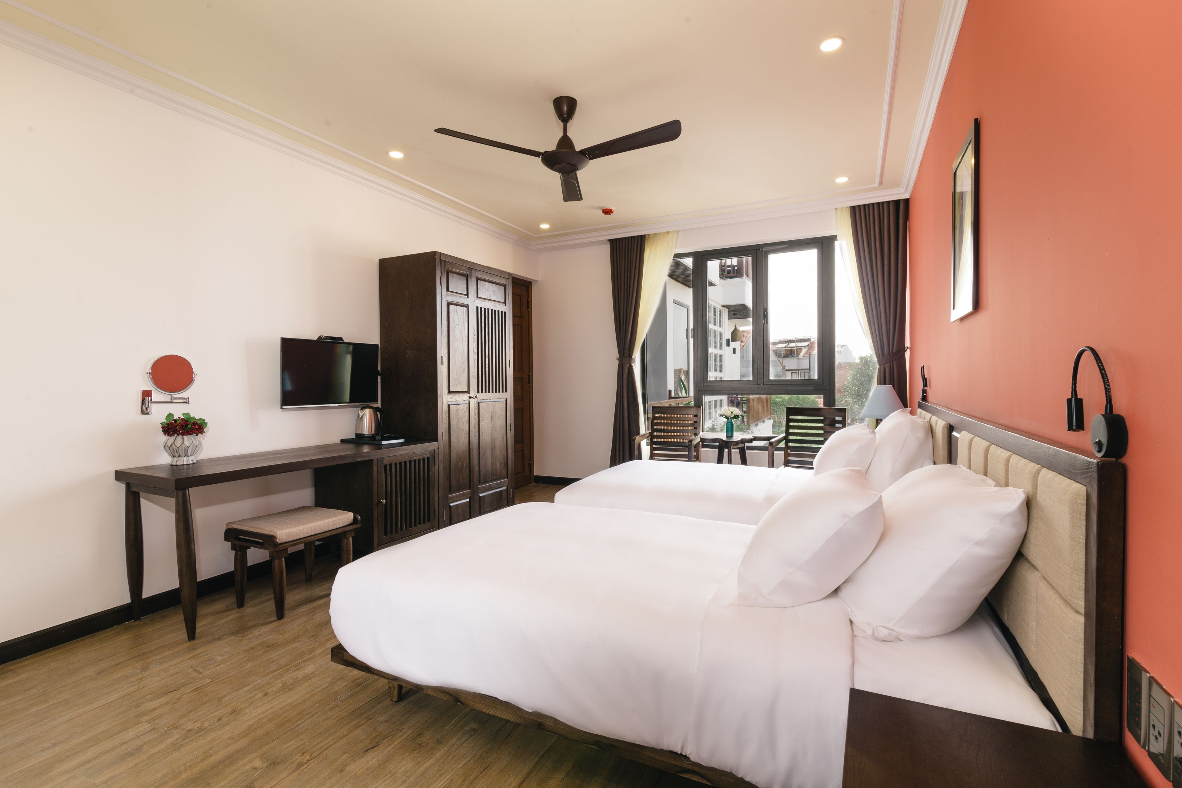 Habitación de hotel con cama, escritorio, silla, televisor y vistas al exterior.