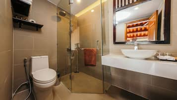 A modern bathroom with a glass-enclosed shower, a white toilet, a large mirror, and a white sink.