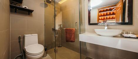 A modern bathroom with a glass-enclosed shower, a white toilet, a large mirror, and a white sink.
