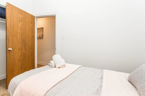 A bedroom with a bed, a wooden door, and a small hallway. - Live Like a Local - Downtown 3 BDR Gem (Chicago)