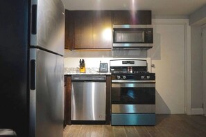 A compact kitchen with stainless steel appliances, including a refrigerator, dishwasher, microwave, and oven. - The Karlov Connection - Ohare Wrigley Gateway (Chicago)