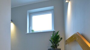 Un escalier orné d’un pot de fleurs, avec une fenêtre et une main courante en bois.