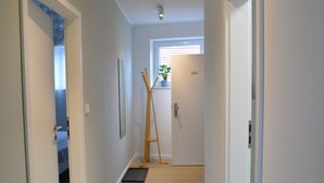 Un couloir étroit doté d’un plancher en bois de couleur claire, de murs blancs et d’une porte portant le numéro 401.