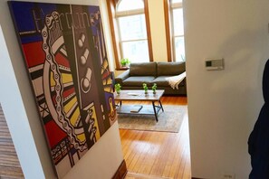 A living room with a sofa, a coffee table with plants, and a large abstract painting on the wall. - Light-filled Chicago Charmer in Wicker Park (Chicago)