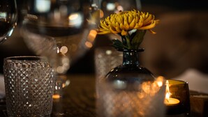 A table setting with a candle, a glass, and a vase with a yellow flower. - The Fox (Winchester)
