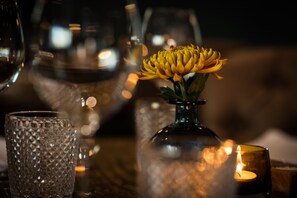 Una mesa dispuesta con una vela, un vaso y un florero con una flor amarilla.