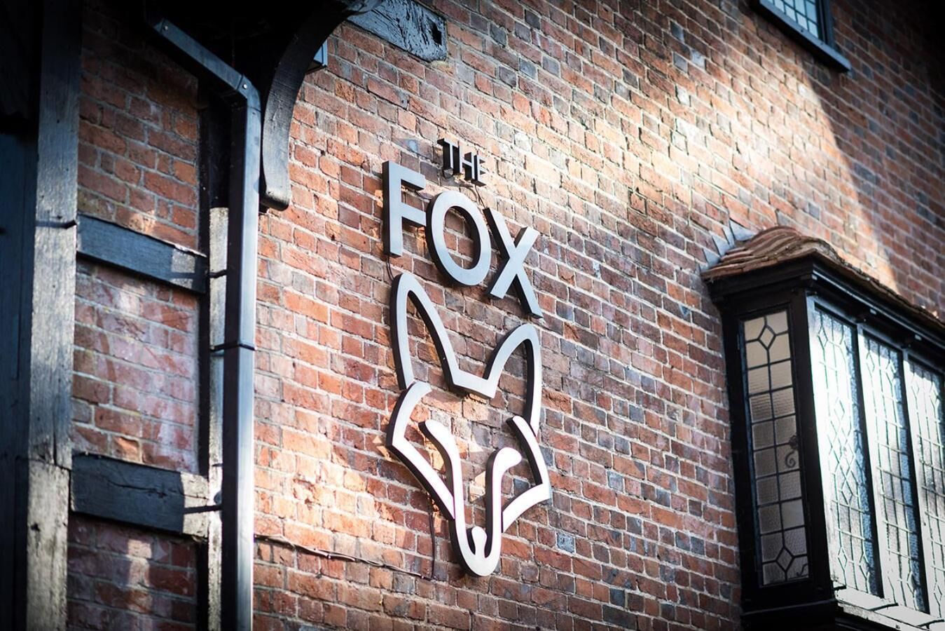 A brick building with a large, white, stylized fox logo on the wall.