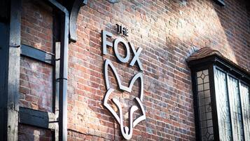 A brick building with a large, white, stylized fox logo on the wall.