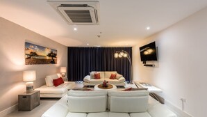 A modern living room with a white sofa, a coffee table, and a TV mounted on the wall. - Las Islas Aruba (Noord)