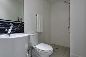 Un baño moderno con inodoro blanco, lavamanos con grifo cromado y zona de ducha.
