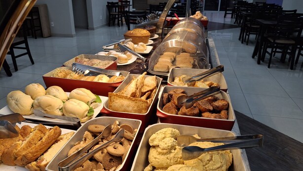 A buffet with various food items including sandwiches, pastries, and fried foods. - Onix Inn Hotel Cravinhos (Cravinhos)