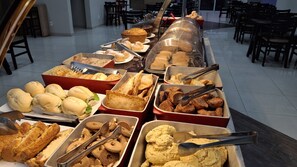 Un buffet proposant une variété de plats, notamment des sandwichs, des pâtisseries et des aliments frits.