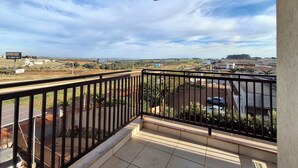 A balcony with a view of a road, buildings, and a distant landscape. - Onix Inn Hotel Cravinhos (Cravinhos)