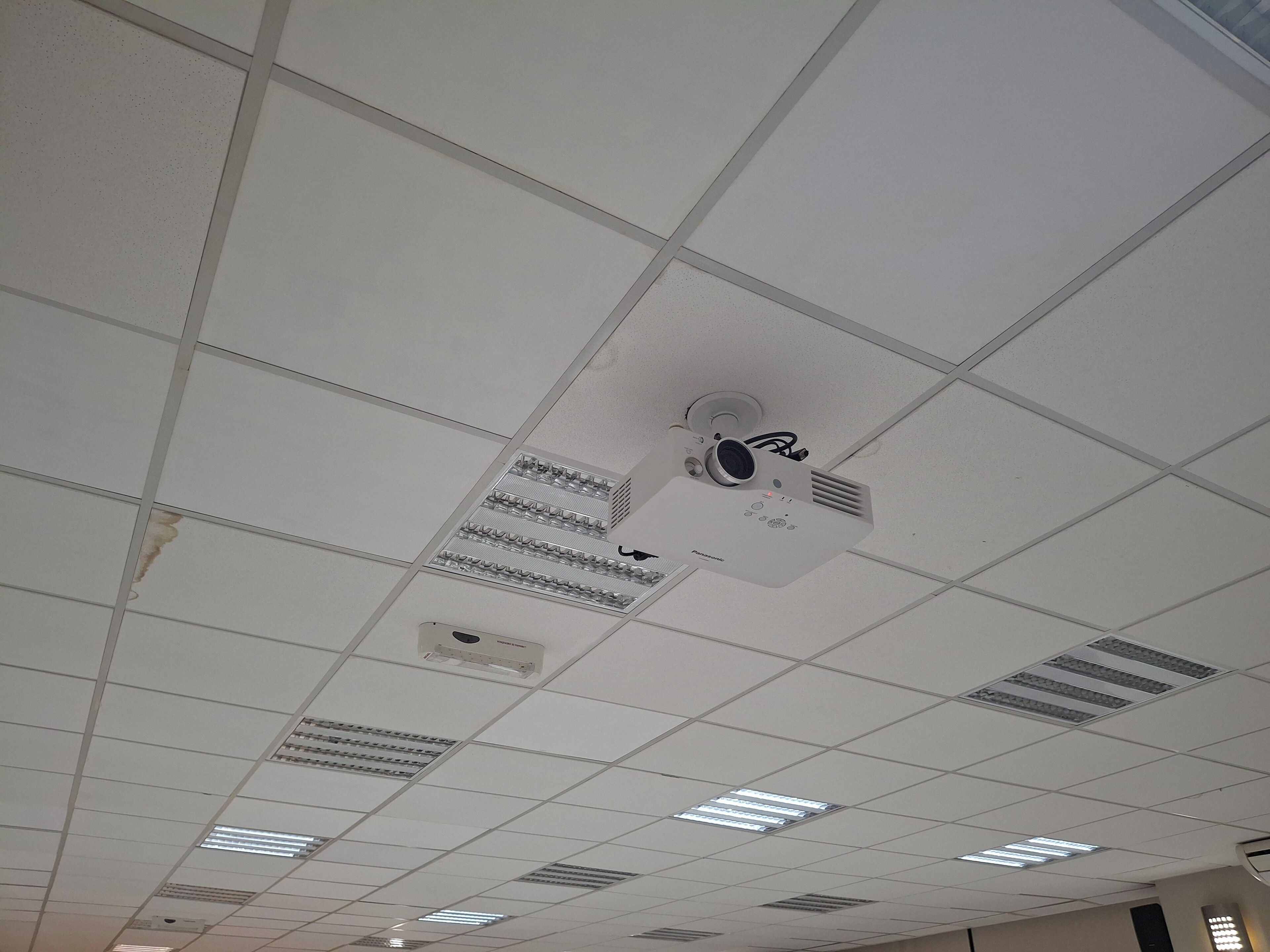 A ceiling with a projector and ventilation ducts.