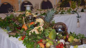 A table set with various fruits and decorative items, including a pineapple, grapes, and a glass bowl. - Hotel Ammerländer Hof (Westerstede)