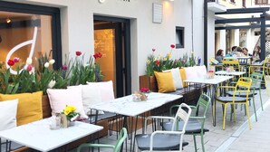 An outdoor cafe with tables and chairs, a sign reading "Figa Garden by Henrik", and potted plants. - Casa Figa 39 (Zagreb)