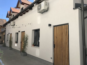 A modern building with a white facade, multiple windows, and a wooden door.