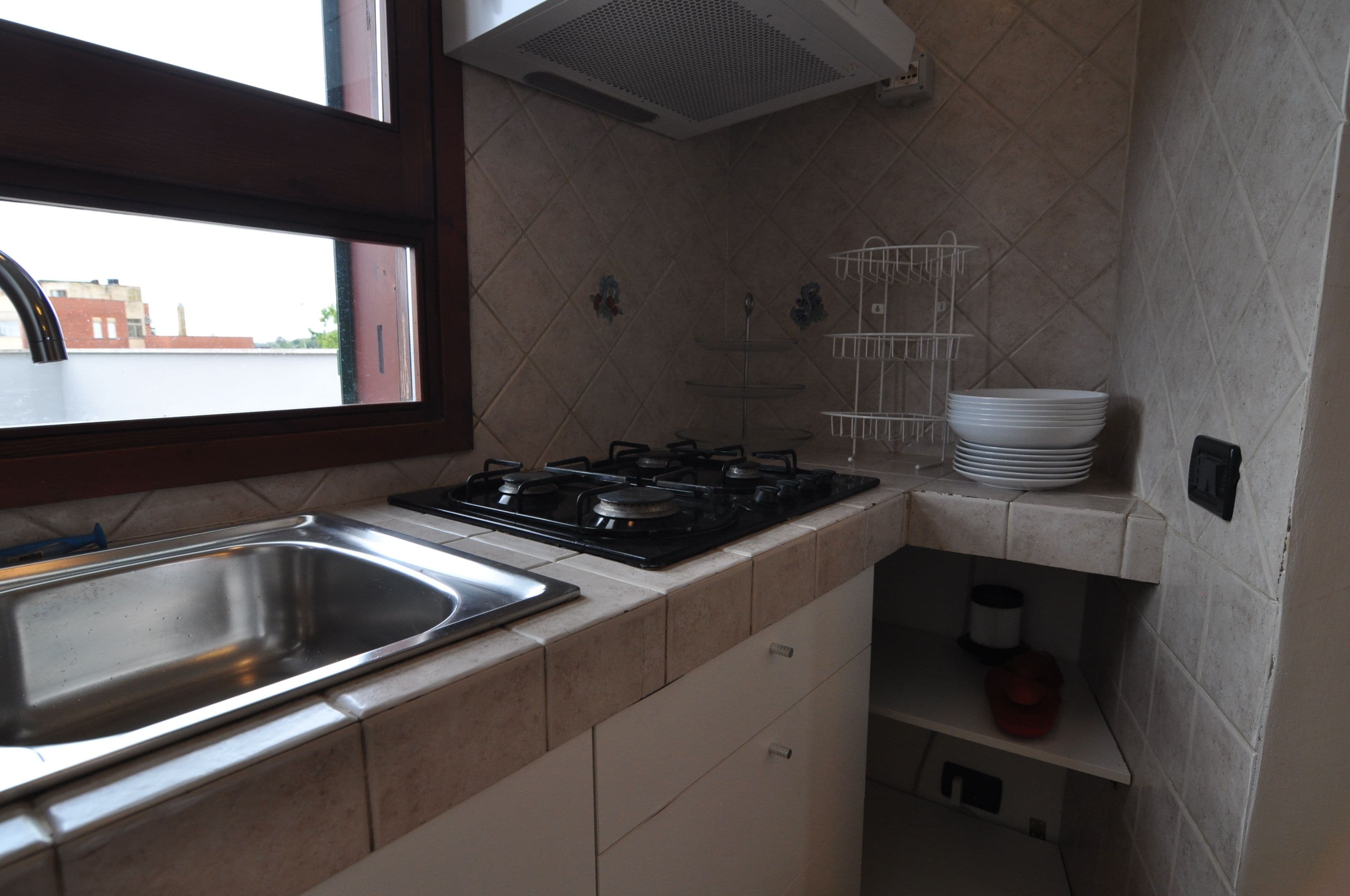 A kitchen with a stainless steel sink, a gas stove, and a dish rack.