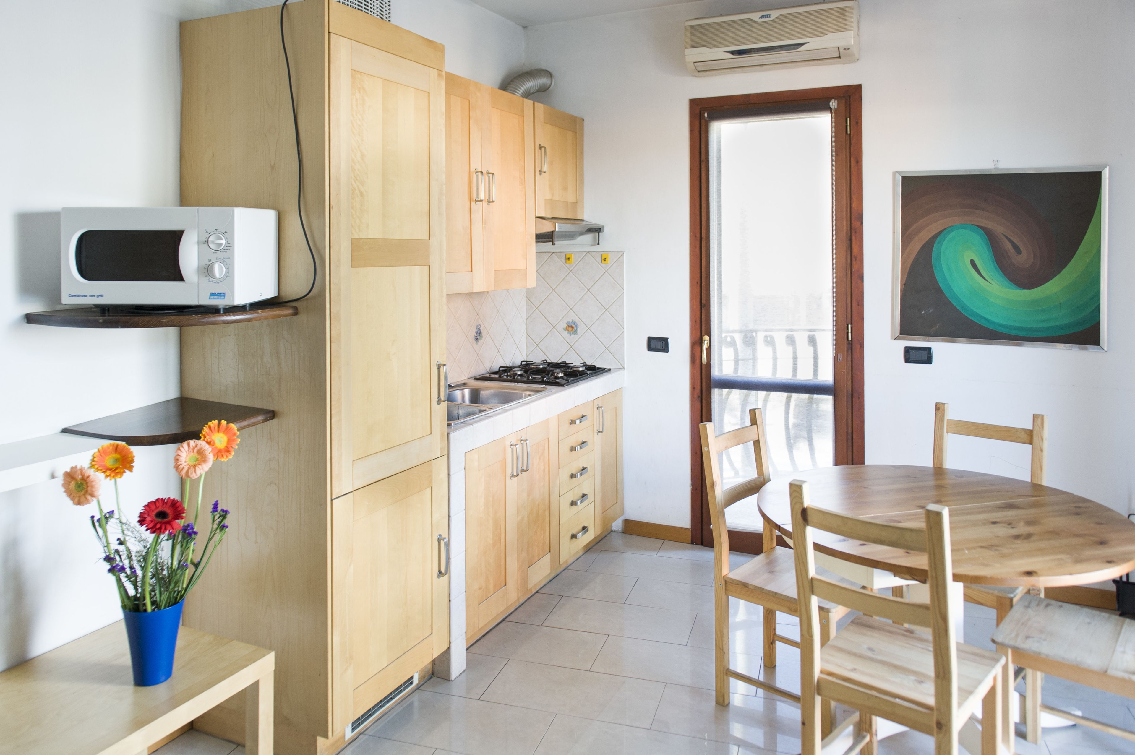 A kitchen with wooden cabinets, a microwave, a gas stove, and a dining table with chairs.
