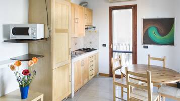 A kitchen with wooden cabinets, a microwave, a gas stove, and a dining table with chairs.