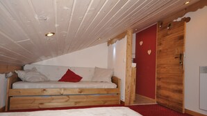 Un lit superposé en bois, avec un mur rouge et une porte en bois.