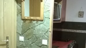 Une cuisine avec un mur en pierre, des armoires en bois et un sol carrelé.