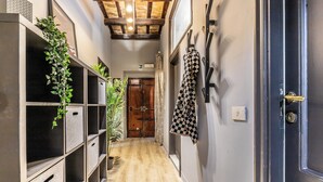 A narrow hallway with wooden flooring, metal storage units, and a door with a black and white checkered towel hanging on the wall. - Flatinrome Trastevere (Rome)