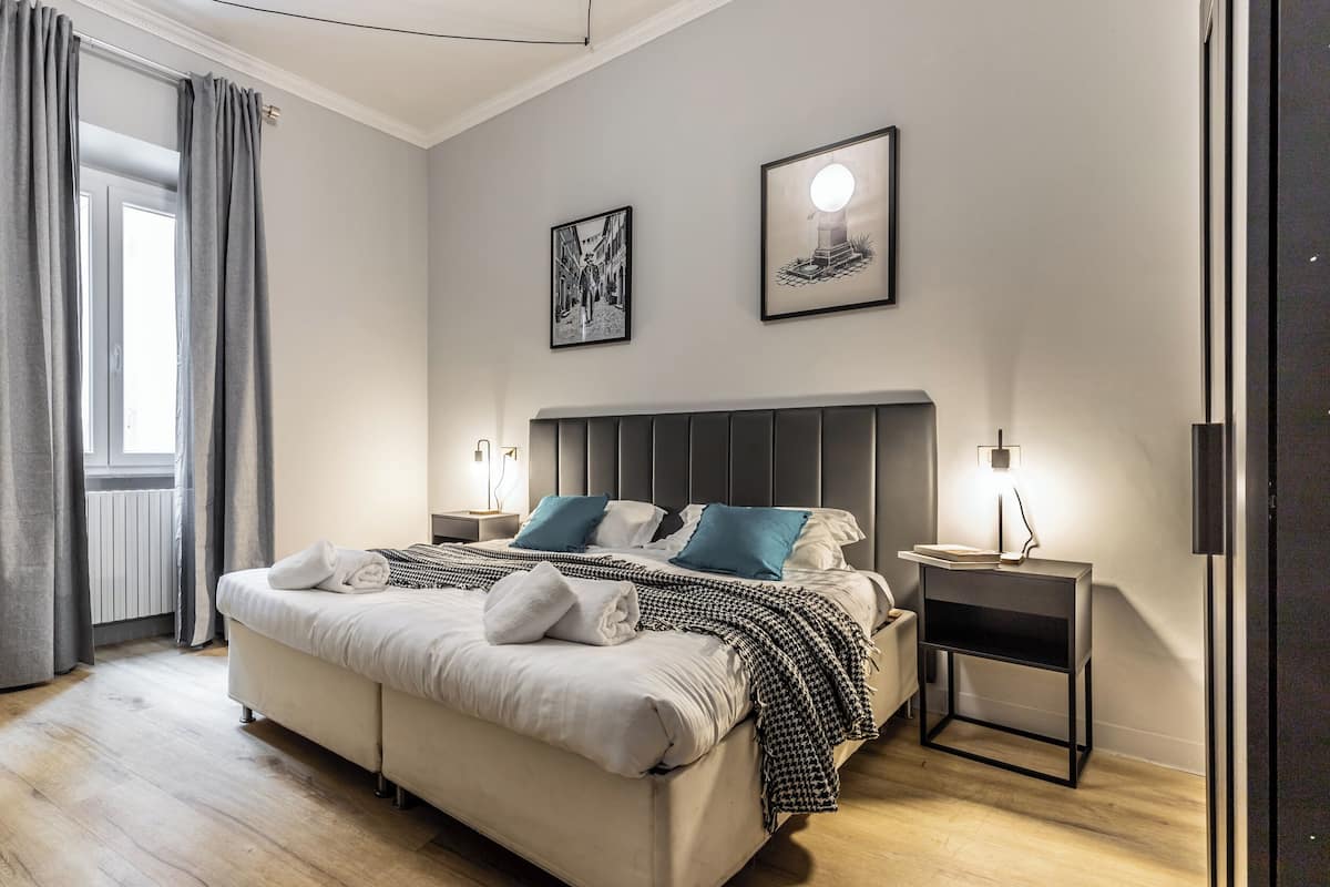 Une chambre à coucher moderne avec un grand lit, des tables de chevet et des œuvres d’art accrochées aux murs.