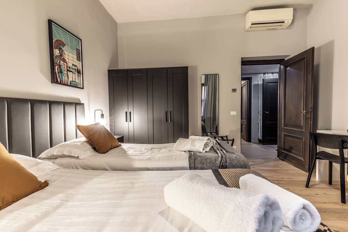 Une chambre d’hôtel avec deux lits, une armoire, un bureau et un appareil de climatisation.