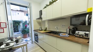 A modern kitchen with white cabinets, a wooden countertop, a kettle, a toaster, and a potted plant. - Flatinrome Trastevere Deluxe Rooms (Rome)