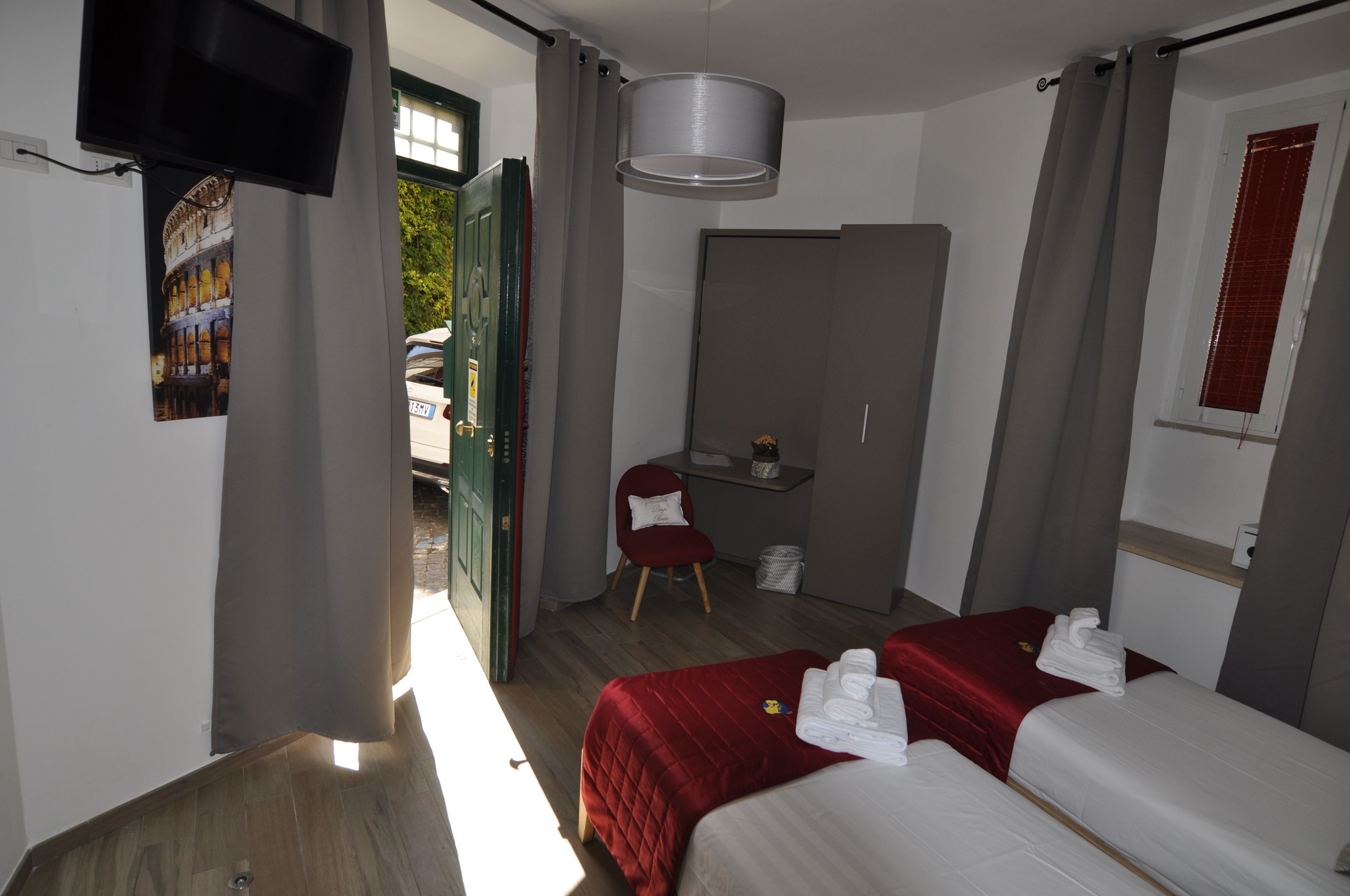 Een hotelkamer met twee bedden, een bureau, een stoel, een televisie en een groot raam.