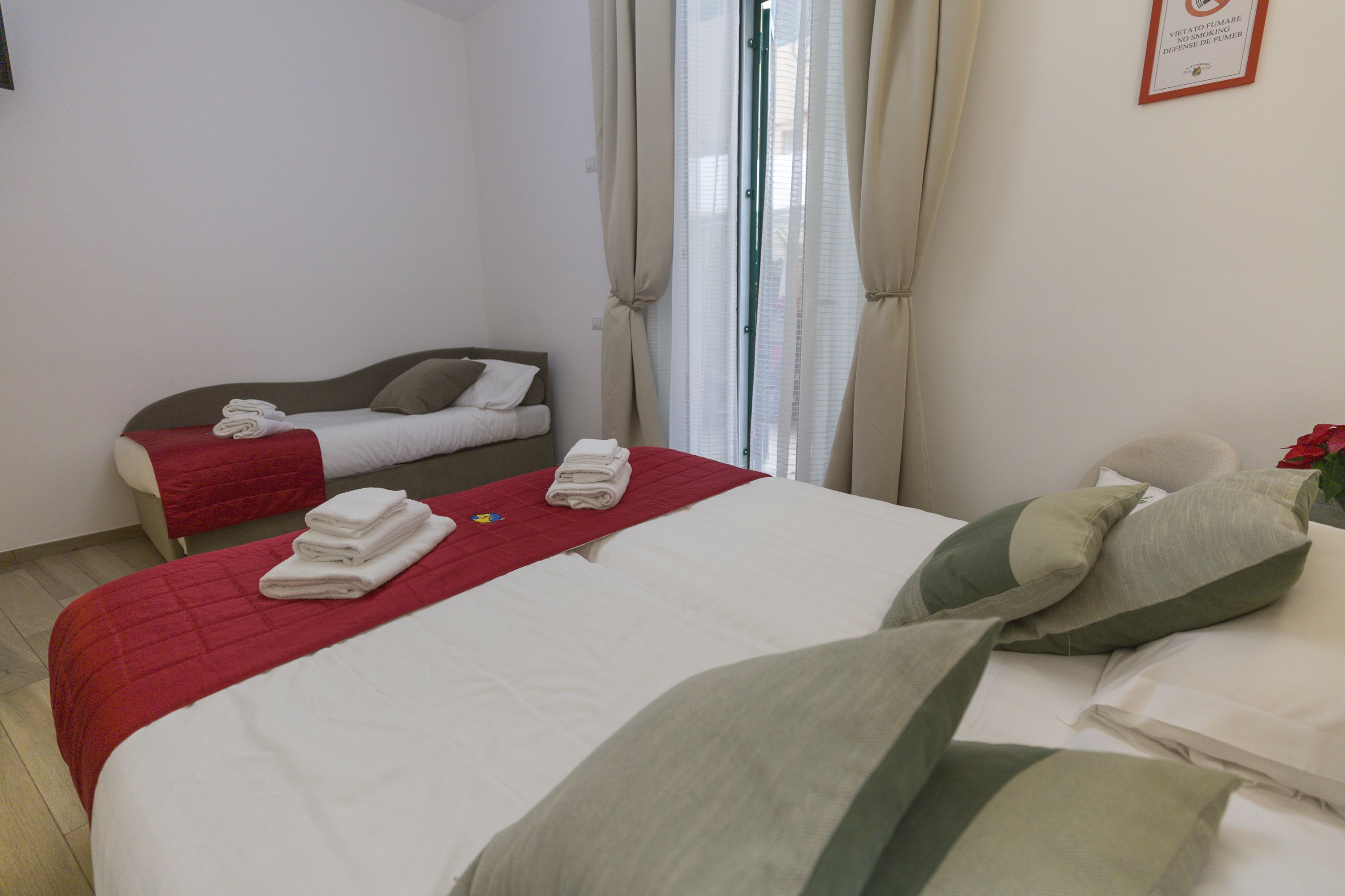A hotel room with two beds, each with neatly folded towels and pillows.