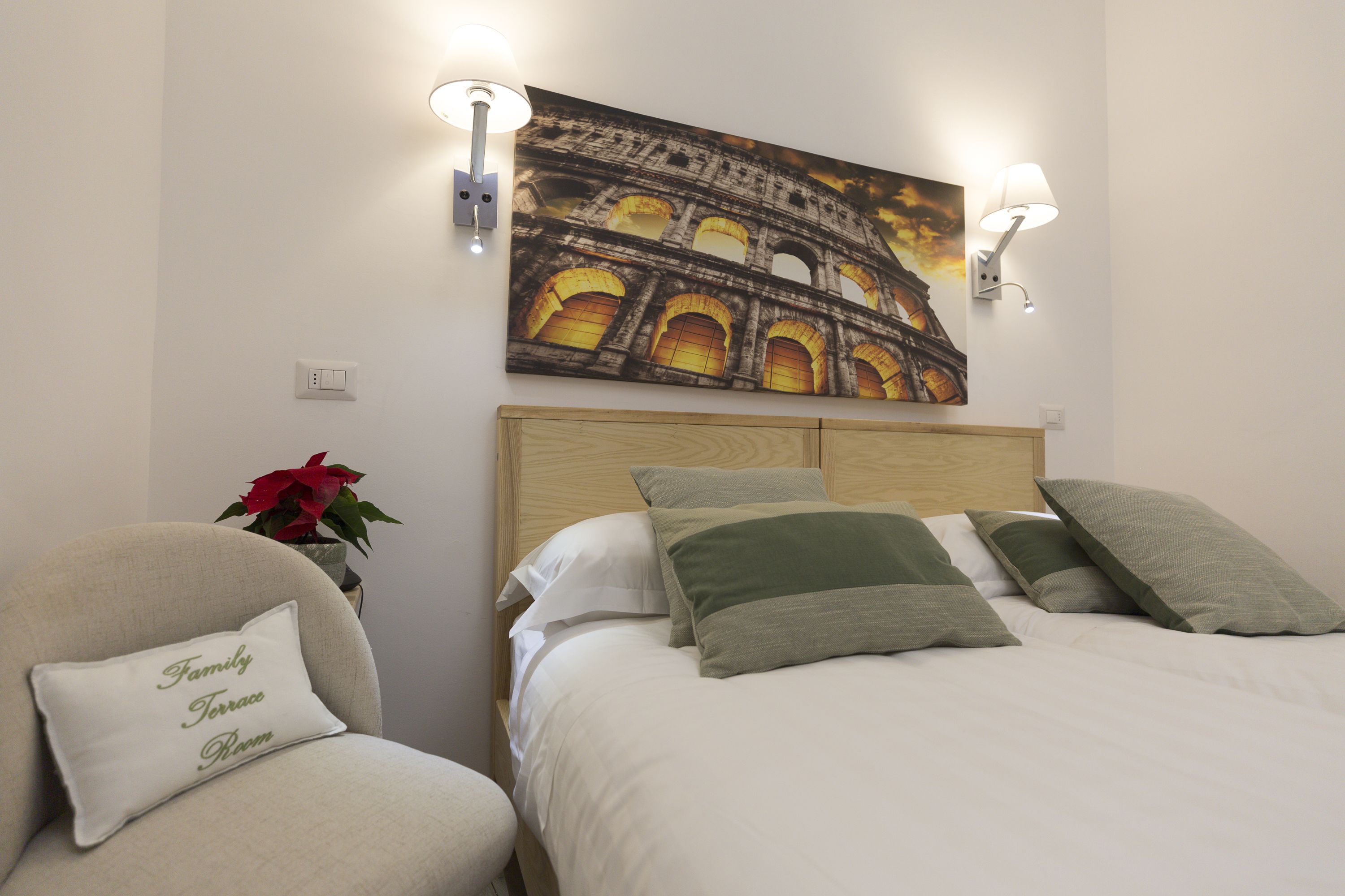 Ein Hotelzimmer mit einem Bett, einem Sessel und einem Gemälde des Kolosseums.