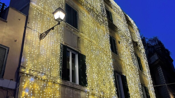 A building facade adorned with string lights, featuring multiple windows and a visible entrance. - Flatinrome Trastevere Deluxe Rooms (Rome)