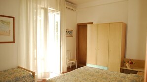 A bedroom with two beds, a wooden wardrobe, a chair, and a window with curtains. - Hotel la Tavernetta dei Ronchi (Massa)