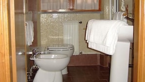 A bathroom with a toilet, bidet, and sink. There is a window with curtains and a towel rack. - Hotel la Tavernetta dei Ronchi (Massa)